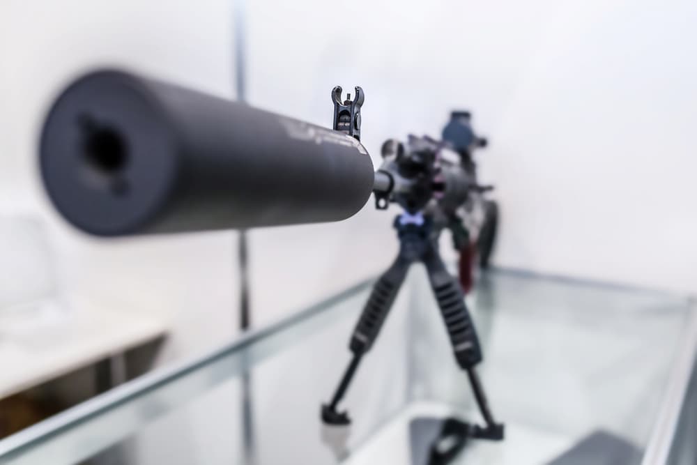 close up photo of gun with a suppressor
